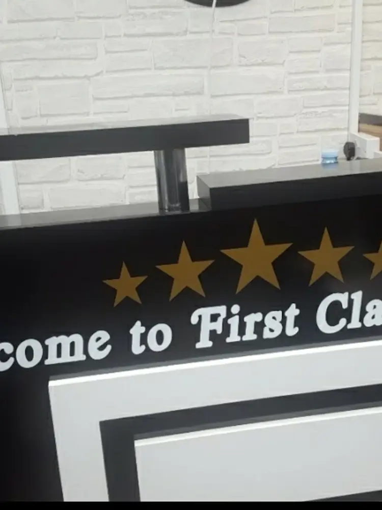 Black reception desk with gold stars and 'Welcome to First Class Barbers' lettering