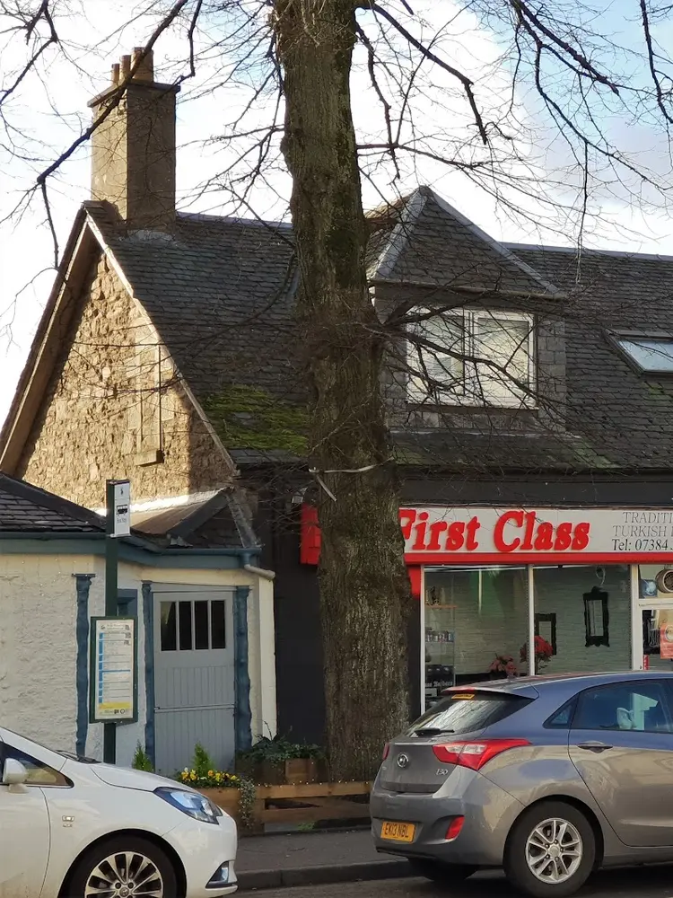 The red First Class shopfront in a row of Bridge of Allan shops
