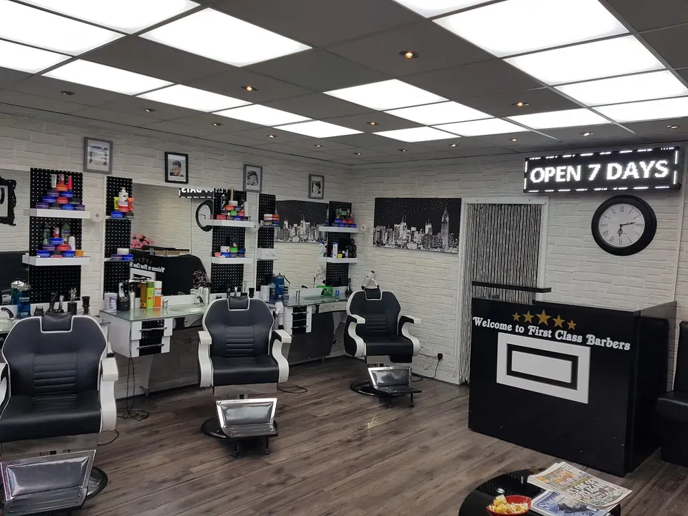 Interior of First Class Barbers with three black and white barber chairs and white brick walls
